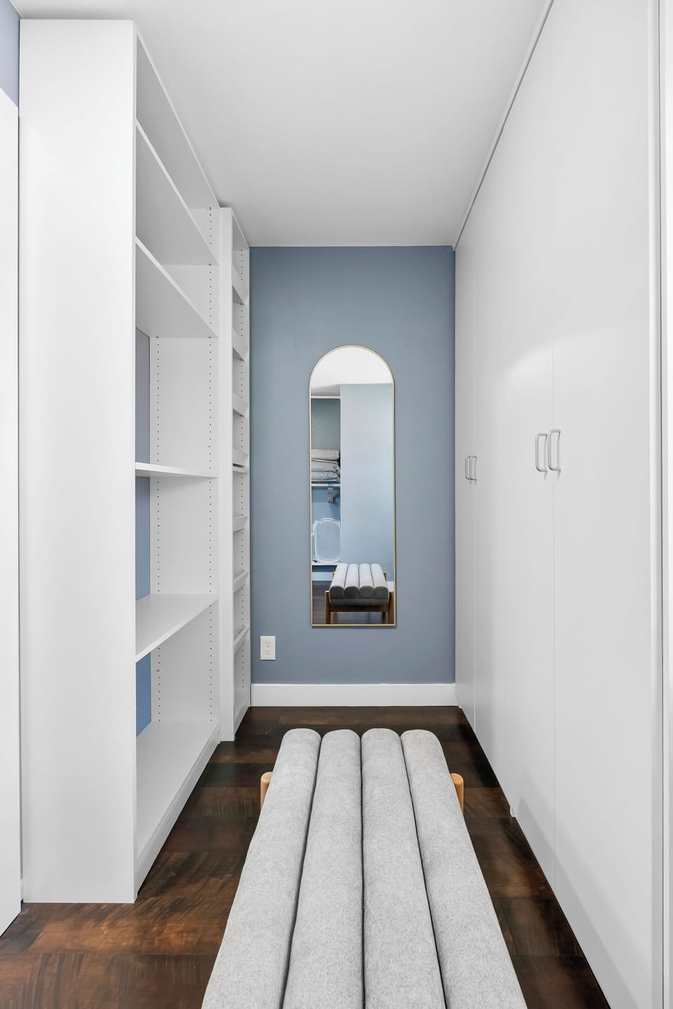 A walk-in closet with a full-body hanging mirror 