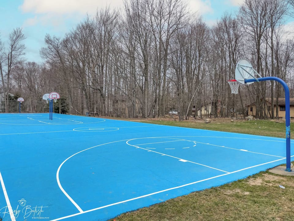 Outdoor Recreation: Shoot some hoops on our vibrant blue court surrounded by nature!
