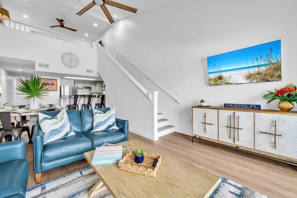 Relax in your bright, airy living space with soaring ceilings, coastal artwork, and stylish furnishings perfect for unwinding after beach adventures.