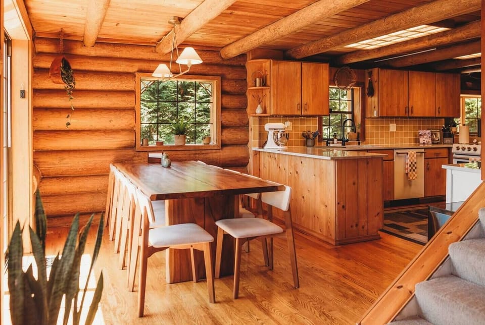 A live edge wood dining table set up for 10 guests with 2 extra chairs to seat up to 12. A Stokke high chair is also stored in the laundry room.