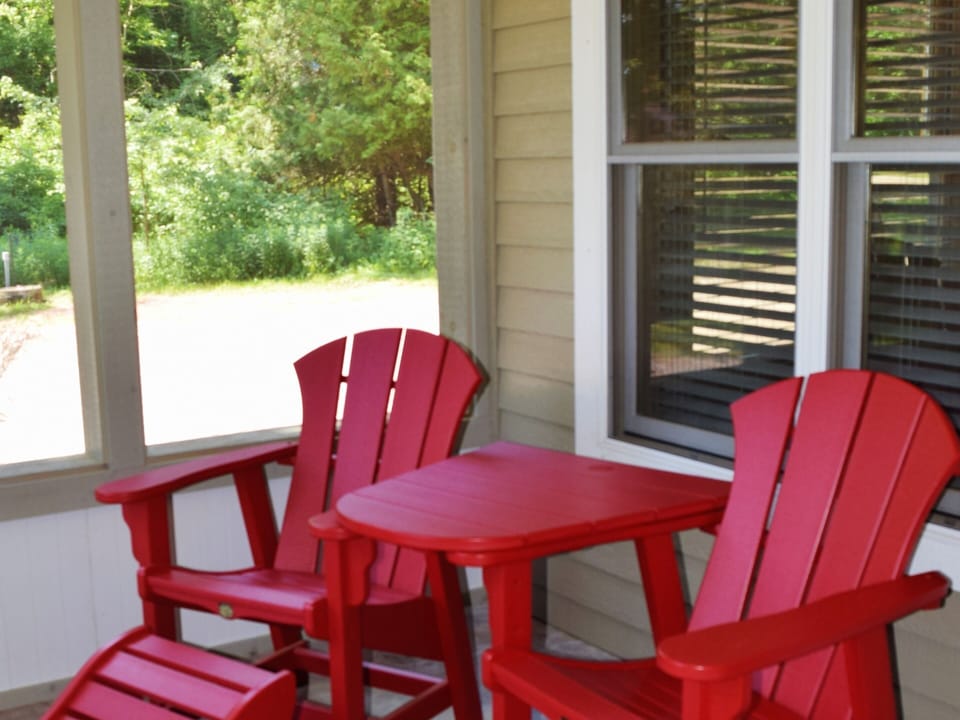 Red Adirondack chairs on the screened in patio