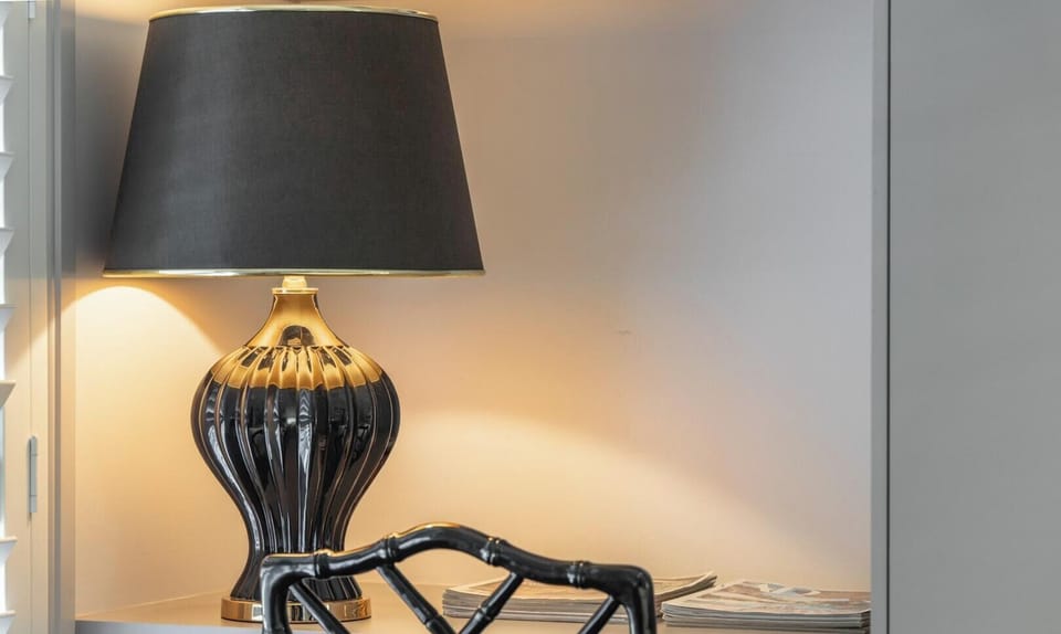 A moody and sophisticated bedside nook featuring an elegant lamp and intricate furniture design.