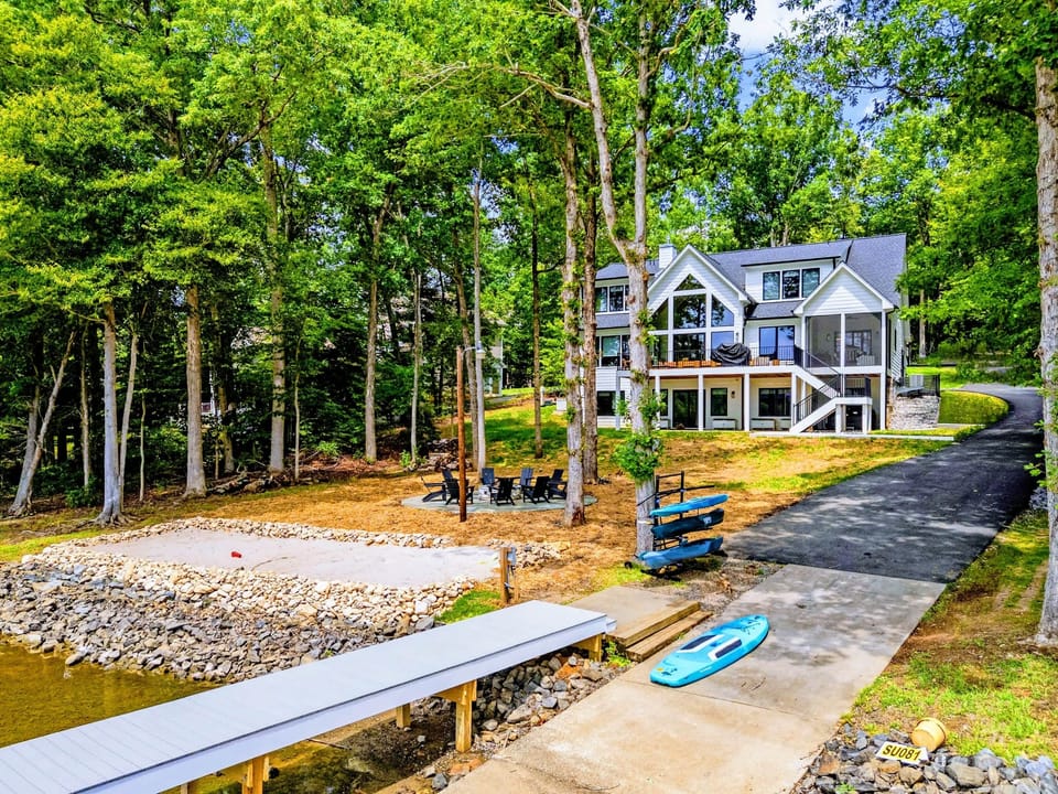 Aerial - The property from above, dock and beach in front, driveway and kayak storage to the side.