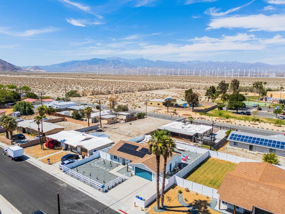 Wide aerial view capturing the neighborhood layout framed by mountains & open desert.