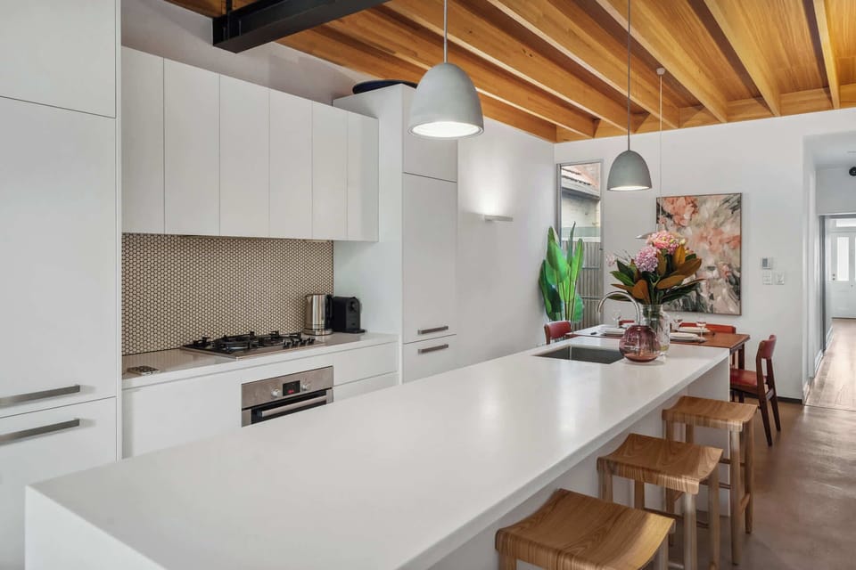 A stunning kitchen blending modern elegance with rustic charm, where the white countertop contrasts beautifully with the warm wooden ceiling.