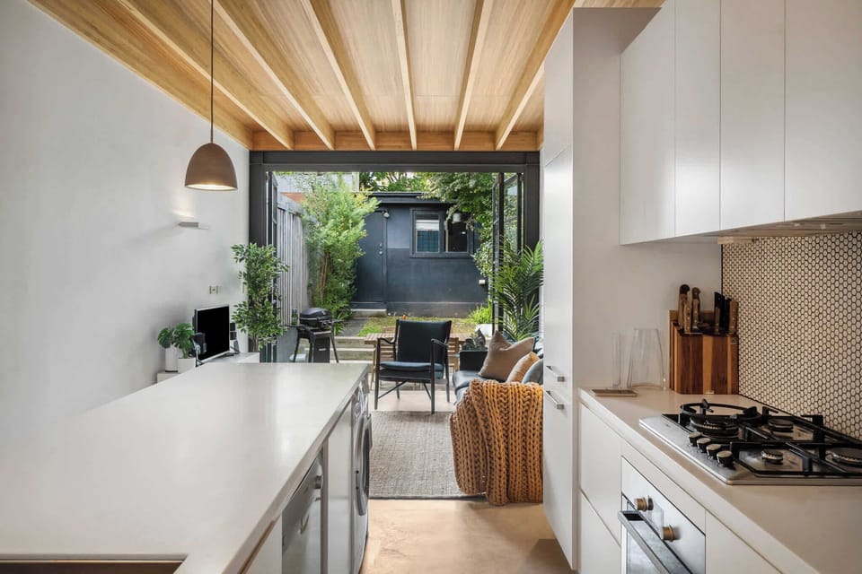 Experience rustic charm meets modern elegance in this stylish kitchen, where a warm timber ceiling complements sleek white surfaces.