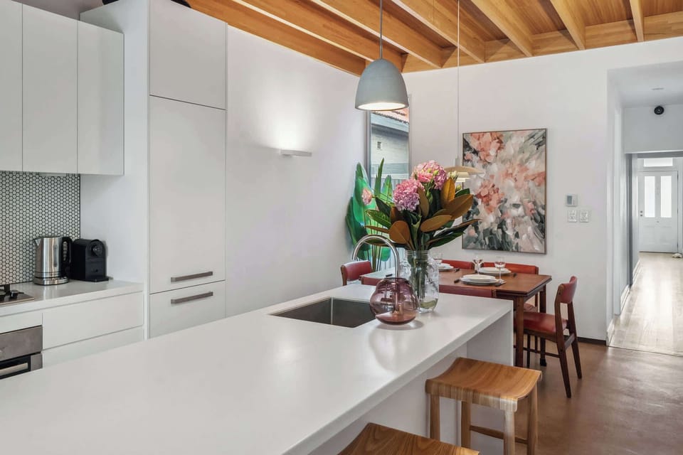 A stunning kitchen blending modern elegance with rustic charm, where the white countertop contrasts beautifully with the warm wooden ceiling.