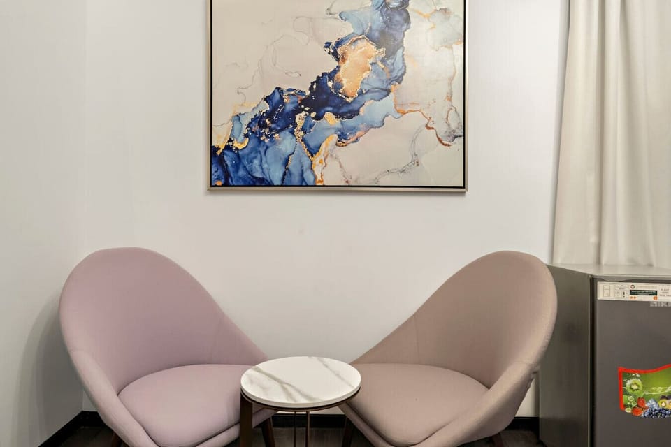 Charming Lounge: Relax in stylish chairs beside a beautiful art piece for perfect downtime!