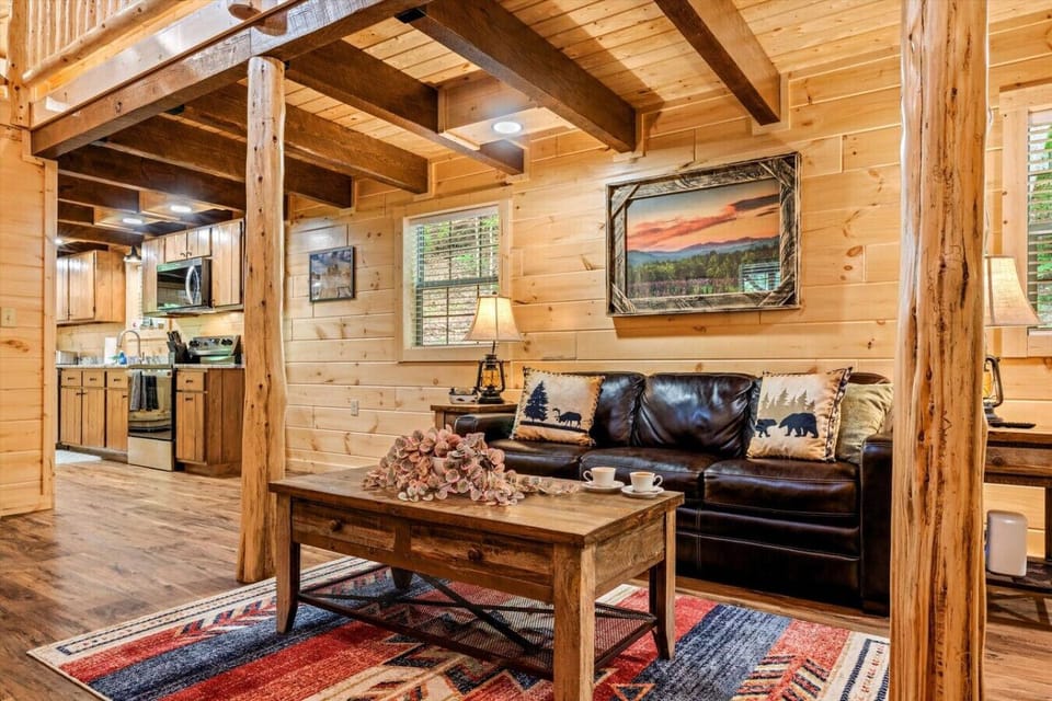 Whether you`re curled up on the couch or gathering with family in the heart of the cabin, this living space invites connection with its exposed beams, custom decor, and soft cabin lighting.