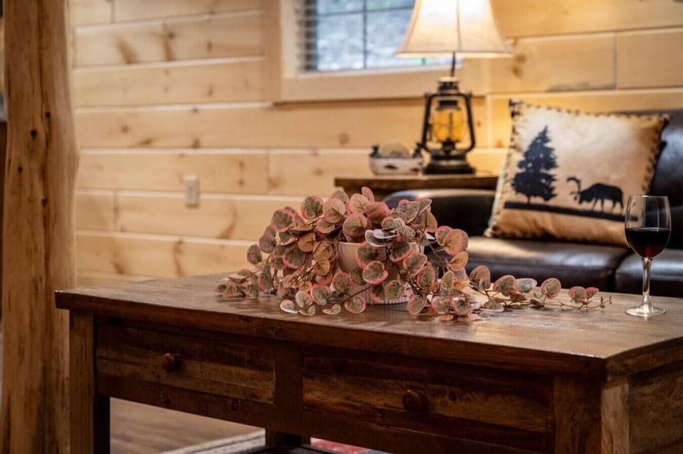 A hand-crafted wooden coffee table, cozy leather seating, and soft ambient lighting create a relaxing mountain lodge feel—perfect for sharing a glass of wine after a day in Pigeon Forge.