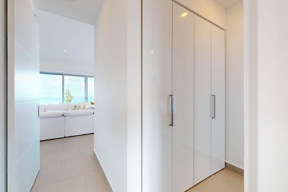 Crisp modern storage flows into a bright living space where blue horizons stretch beyond, creating a seamless, airy retreat for your coastal escape.