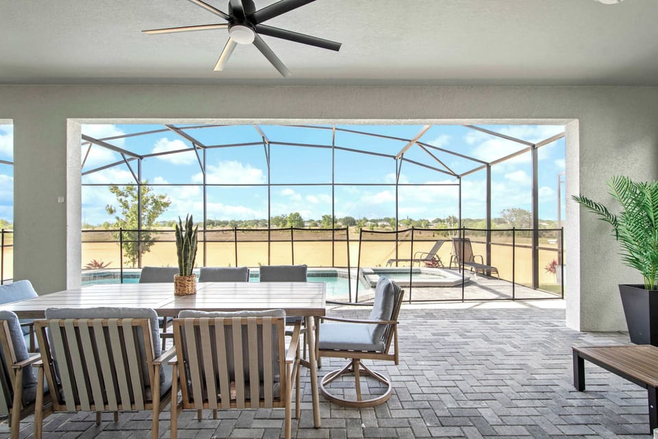 Modern lanai with screened pool, dining area, and serene outdoor views.