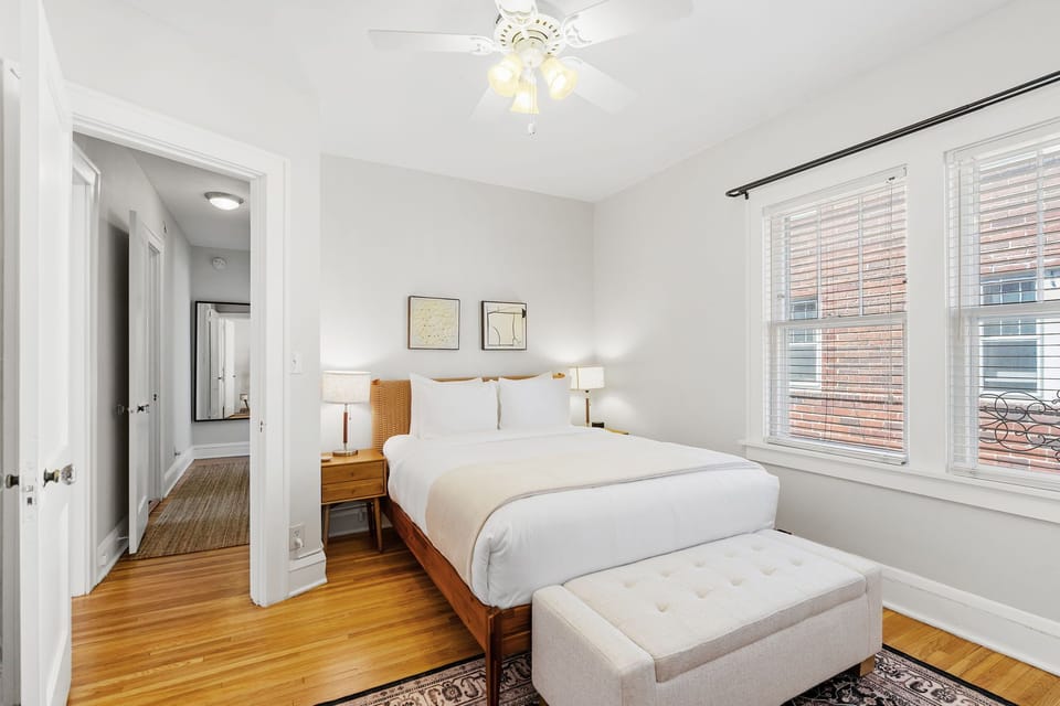 Sink into crisp white linens and warm wood tones in your peaceful retreat, where morning light streams through large windows.