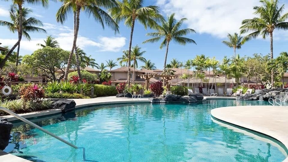 Tropical paradise pool with swaying palms, lava rock accents, and beautiful garden surroundings.