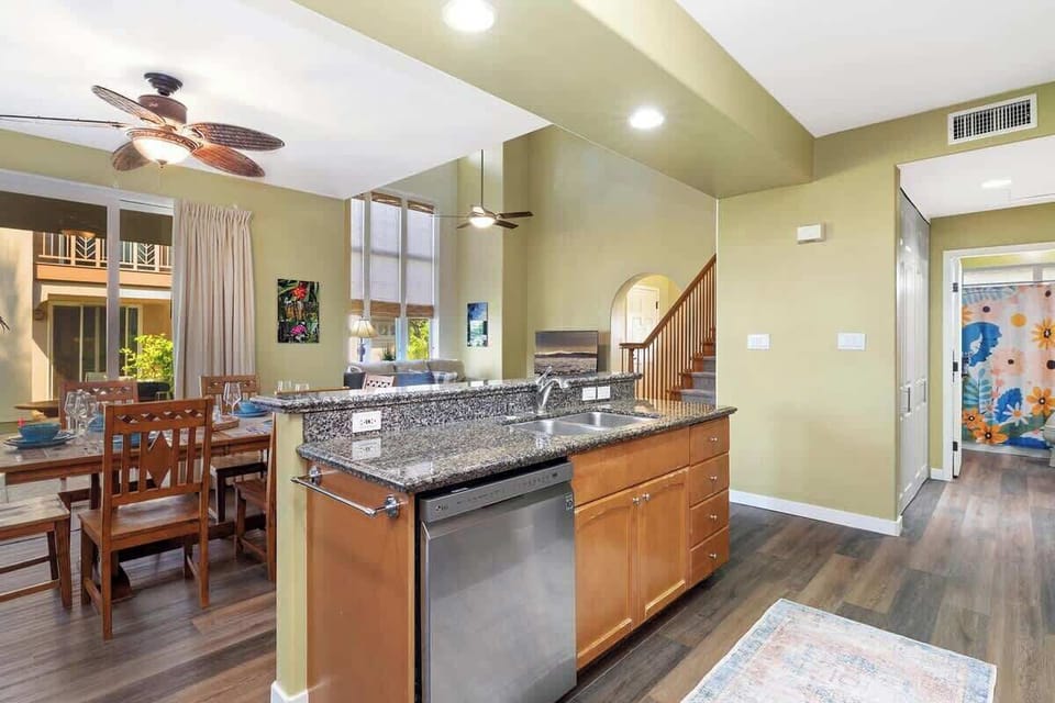 Central island with dual sink overlooks the open layout with access to colorful bathroom and stairs.

