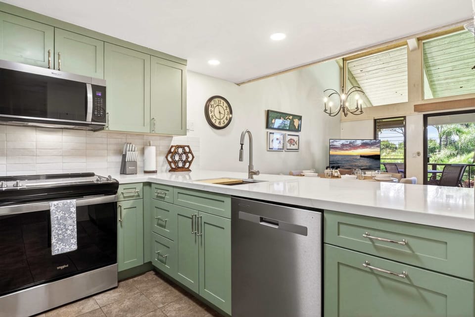 Functional kitchen includes full size stove, microwave, dishwasher, and tiled backsplash wall.