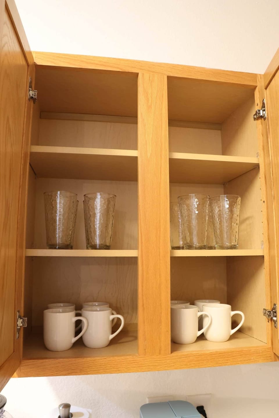 Kitchen cabinet stocked with glassware and mugs, ensuring all the essentials for your morning coffee or evening beverages. Perfect for guests staying long-term or those exploring nearby attractions like Lewisville Lake and Aubrey's local dining spots