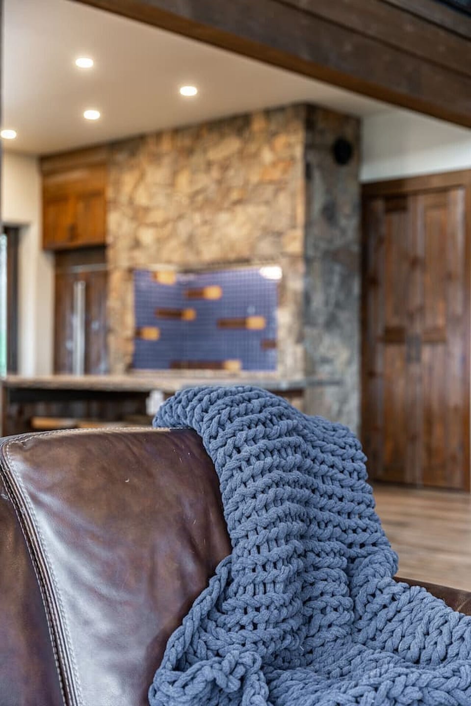 Gather in the soaring great room with timber beams, leather seating, and a 20-ft stone hearth — perfect for deep connection, movie nights, or wine by the fire.
