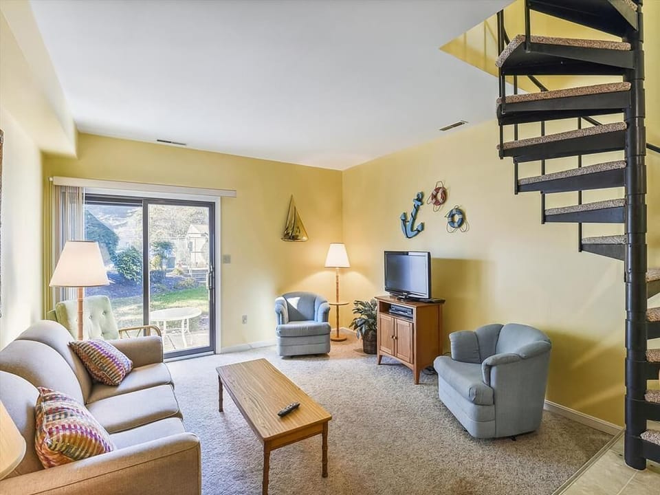 Relax in the cozy living room adorned with coastal decor, complete with plush seating and large windows offering serene views of the outdoors.