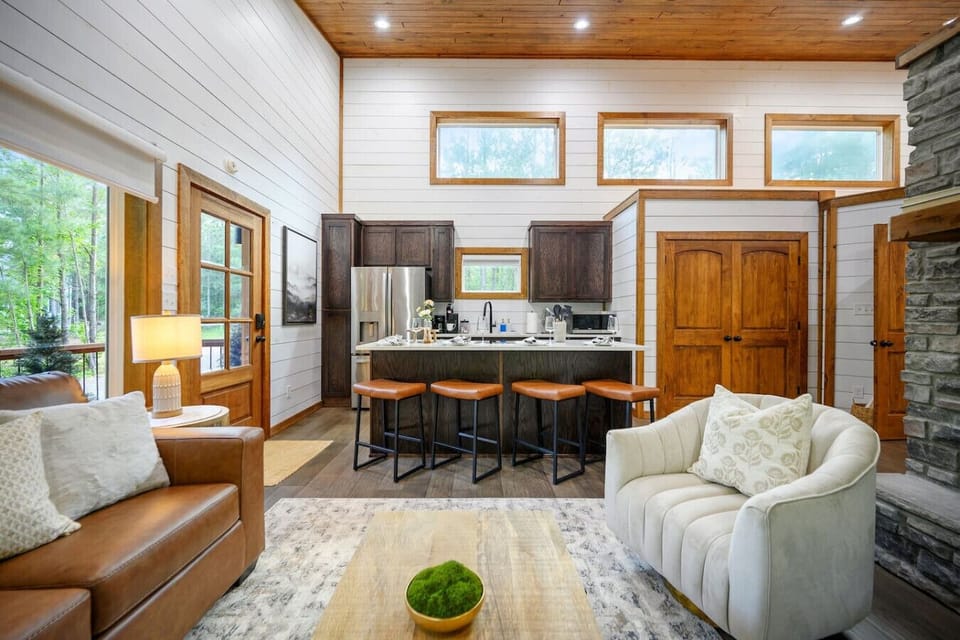This open-concept living space is basically the heart of the cabin—kitchen, dining, lounge, and those killer forest views all flowing together so naturally that you`ll never want to cook or hang out anywhere else.