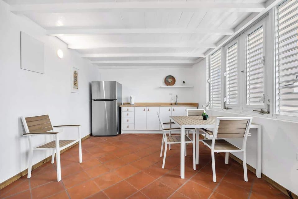 This space features a stylish dining set and a practical kitchenette equipped with a full-sized stainless steel refrigerator and ample counter space.