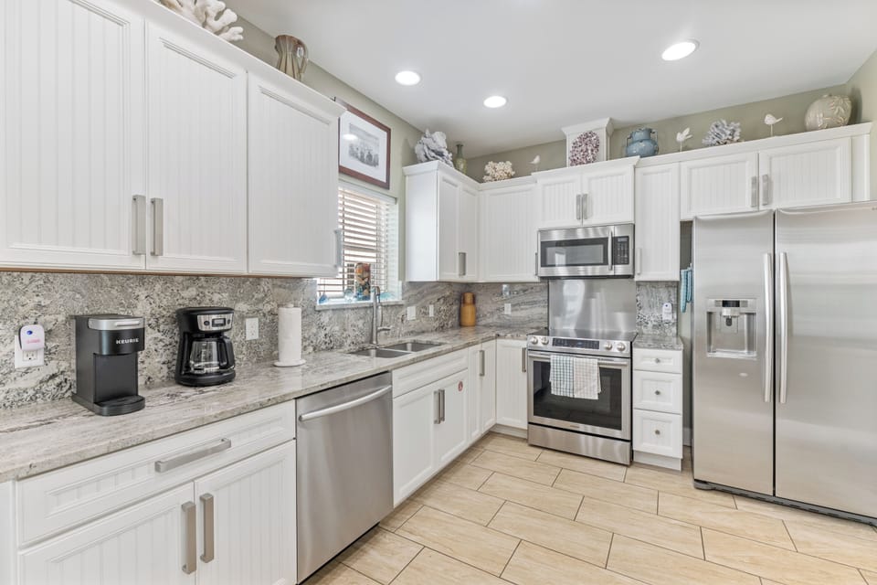 Your fully equipped gourmet kitchen awaits with gleaming granite countertops, stainless steel appliances, and coastal-inspired décor for memorable meals.
