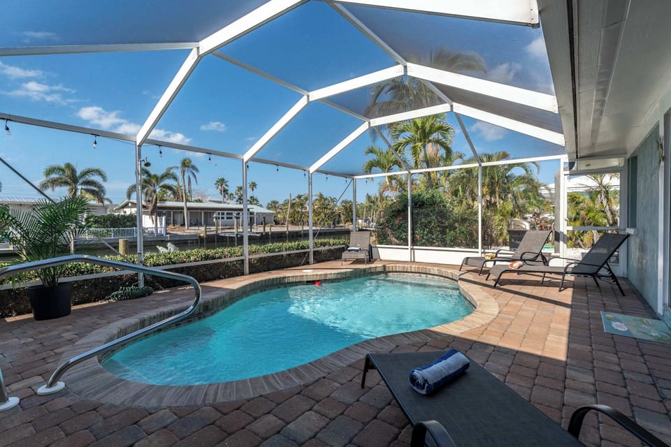 This sparkling  pool is surrounded by comfy lounge chairs, tropical landscaping, and tranquil canal views all framed by a spacious lanai. Whether you're sipping morning coffee poolside or enjoying an evening swim under the string lights.
