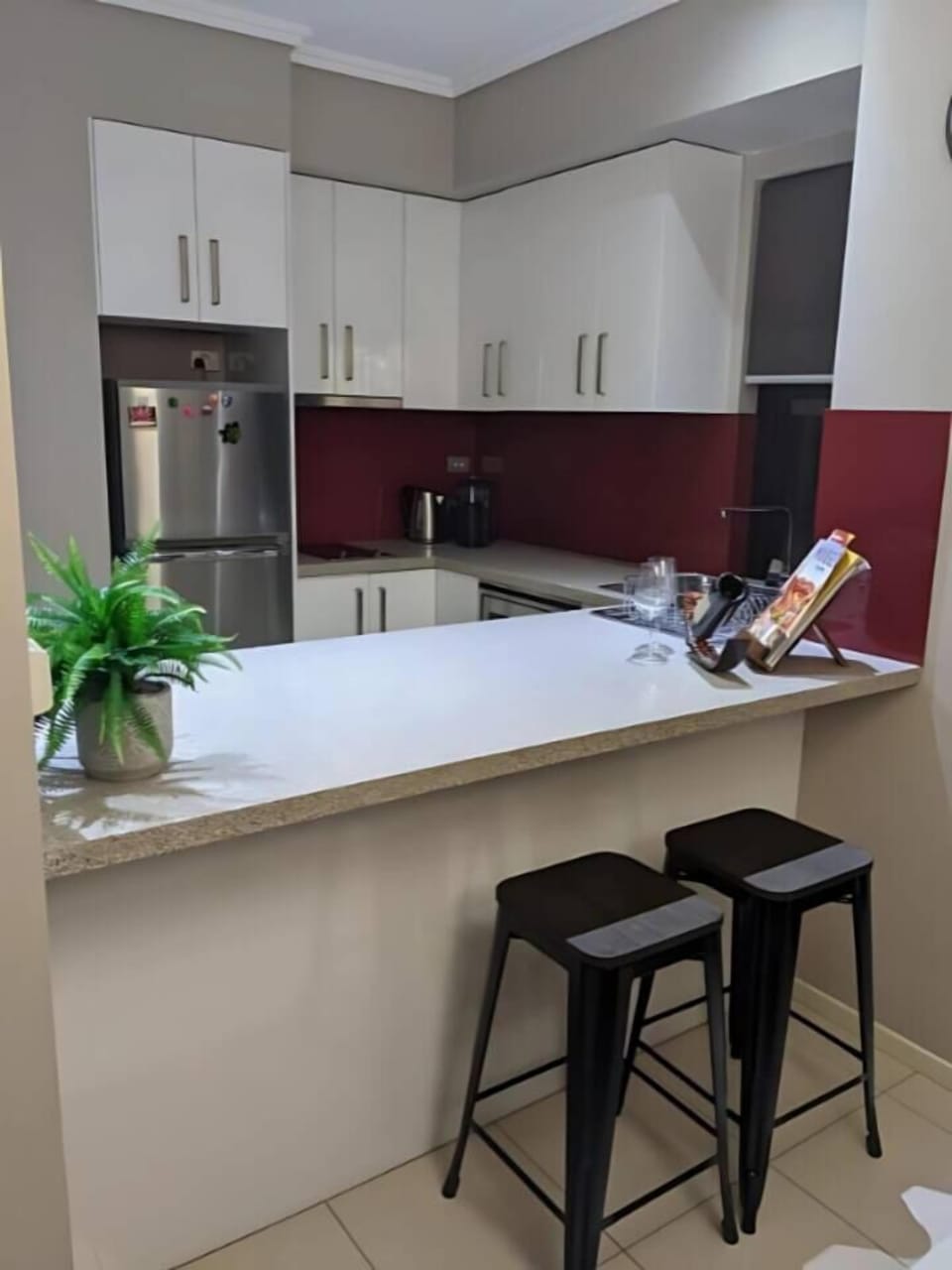 The stone kitchen bench paired with bar stools creates a cosy nook for casual breakfasts, quick bites, or an evening glass of wine.
