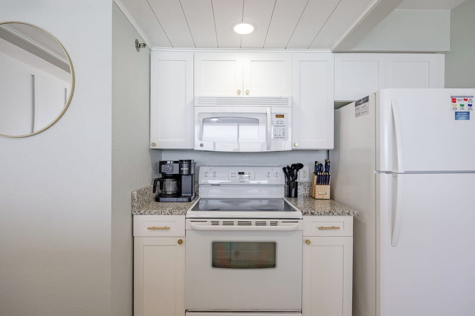 Compact kitchen area with white appliances and granite countertops.