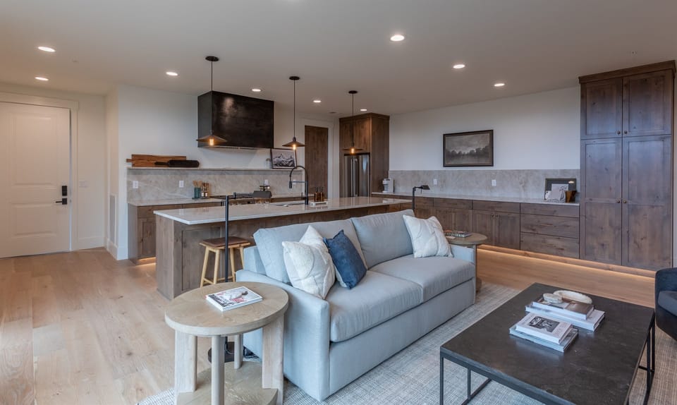 Stylish living room with warm wood accents, modern furnishings, and open flow into the kitchen.