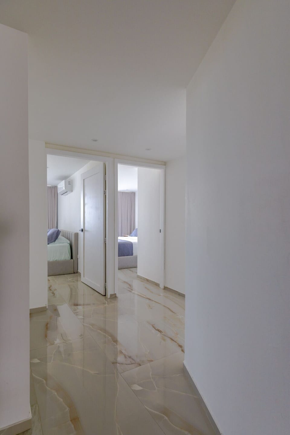The corridor leading to the private area of the apartment is quite inviting. It has a warm tone, with soft lighting and tasteful artwork adorning the walls.