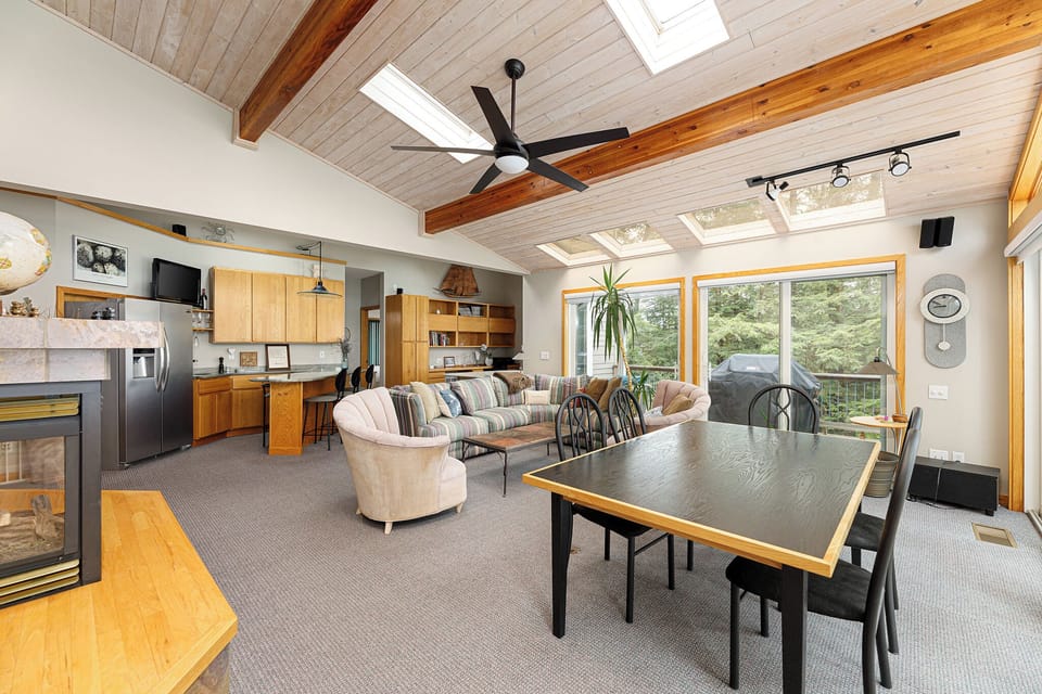 From the cozy sectional to the dining table, this open layout ensures everyone feels connected while enjoying the beautiful surroundings visible through the large windows.