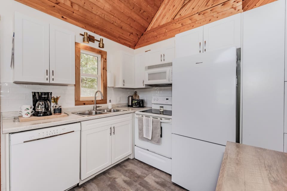 Fully equipped modern kitchen featuring white cabinetry, updated appliances, and all essentials for an easy and relaxing cottage vacation.