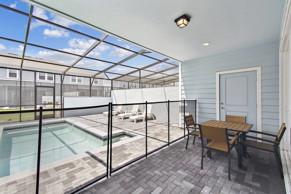 Step outside to a charming screened-in patio, where a cozy table awaits your morning coffee. Enjoy the inviting view of the sparkling pool surrounded by sleek pavers, perfect for relaxing in the sun or gathering with friends.