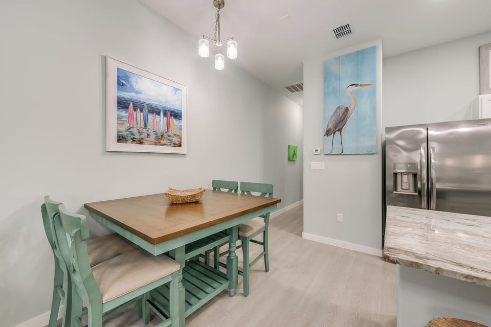 Your bright dining area features coastal artwork and a charming mint green table, perfect for morning coffee or evening meals with loved ones.