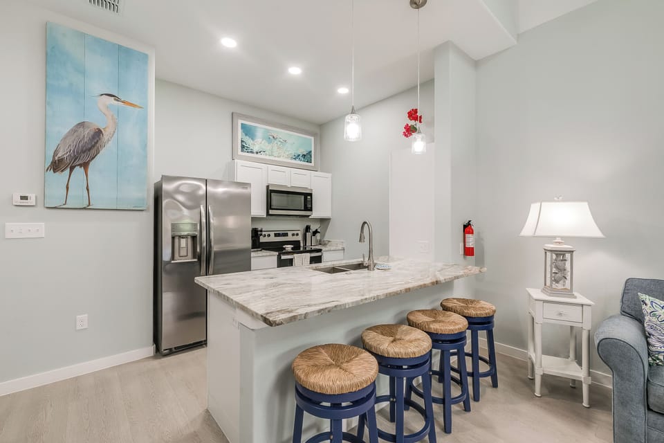 Cook your favorite meals in this bright, modern kitchen featuring granite countertops, stainless appliances, and cheerful blue bar stools for casual dining.