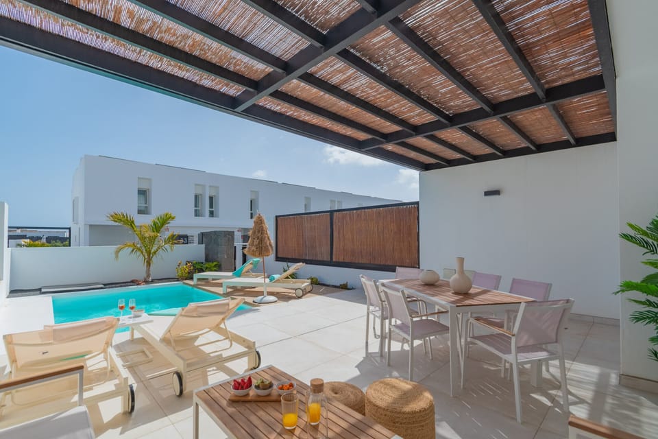 Shaded outdoor dining area under a wooden pergola.