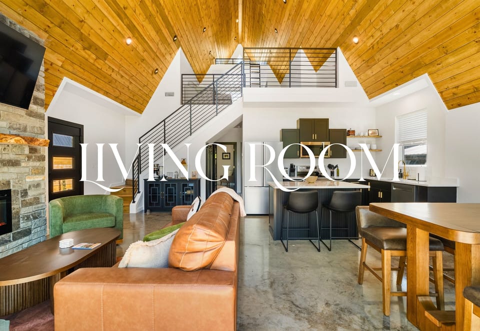 With oversized windows, cozy furniture, and wood-lined ceilings, the living room feels both expansive and grounded.