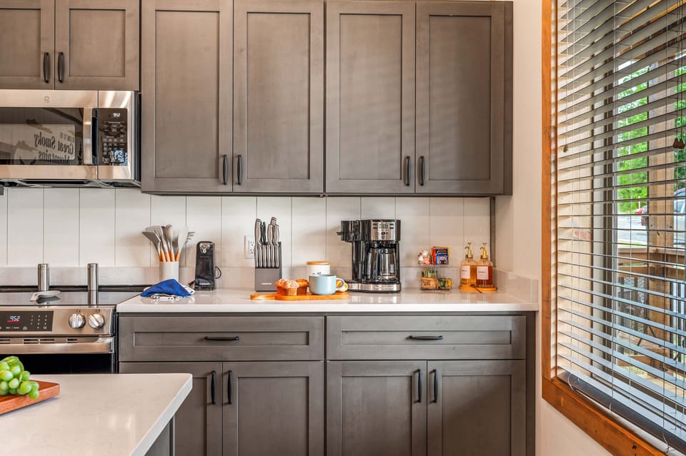 Stylish kitchen with dark cabinets, sleek counters & cozy coffee station setup.