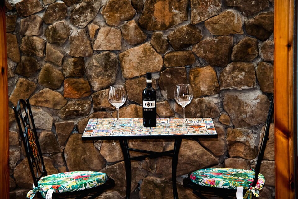 Furniture, Wood Stain, Stone Wall, Chair, Bottle, Still Life Photography, Outdoor Table, Still Life, Glass Bottle