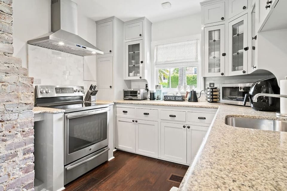 Bright and modern kitchen features white cabinetry, stainless steel appliances, and a large countertop, perfect for culinary adventures.
