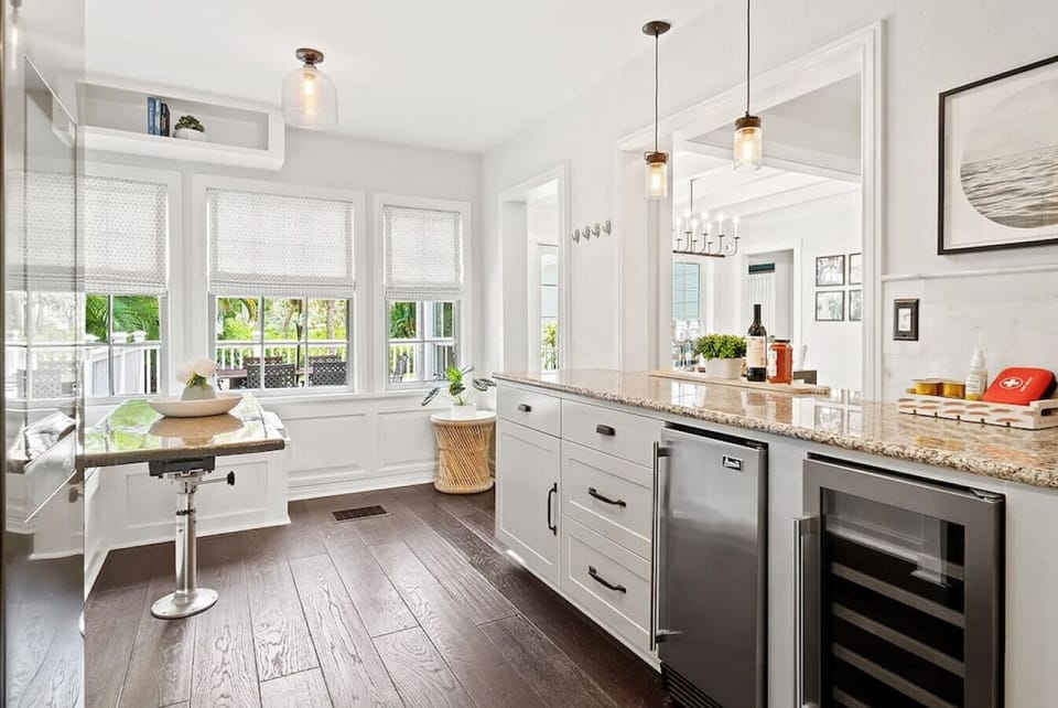 Open living area showcases a dining table by large windows and a modern kitchen with stainless steel appliances.
