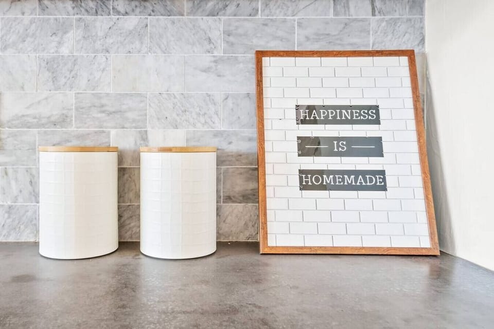 Stylish countertop features two cylindrical containers and a framed "Happiness is Homemade" print, adding a personal touch.
