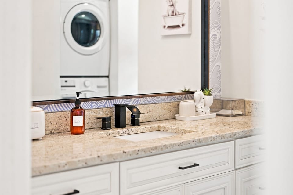 Elegant bathroom vanity with granite countertops and a stacked washer/dryer.