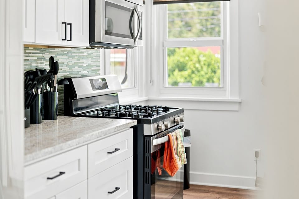 Kitchen detail highlighting the stainless gas range and garden window views.