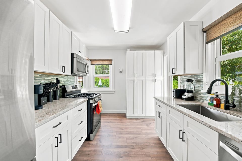 Bright, updated kitchen featuring white cabinetry, granite counters, and stainless steel appliances.