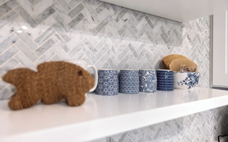 Beautiful herringbone backsplash and charming blue ceramic containers create your perfect cooking backdrop.