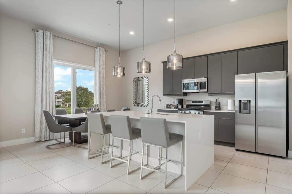 Modern kitchen with stainless steel appliances, island seating, and dining area. Perfect for extended stays, offering comfort and convenience in a stylish space. Enjoy cooking, dining, and relaxing in this bright, spacious home. Book your stay now!