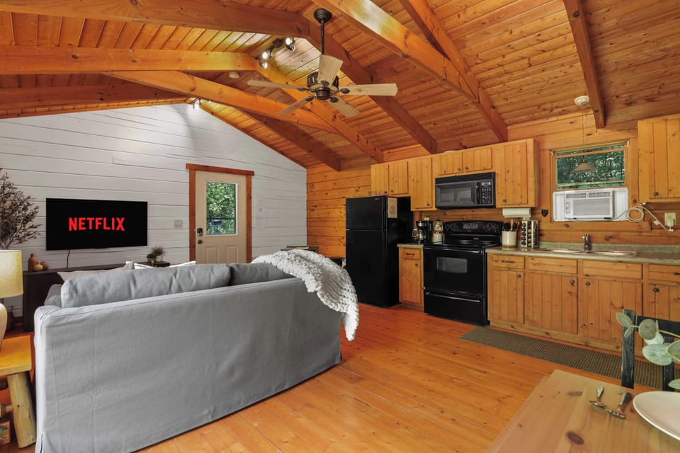 Open concept living with pull out couch, smart tv, board games, pellet stove, and stocked kitchen. Please note this cabin has a window AC unit and portable fans only. There is no central air in the small cabin.