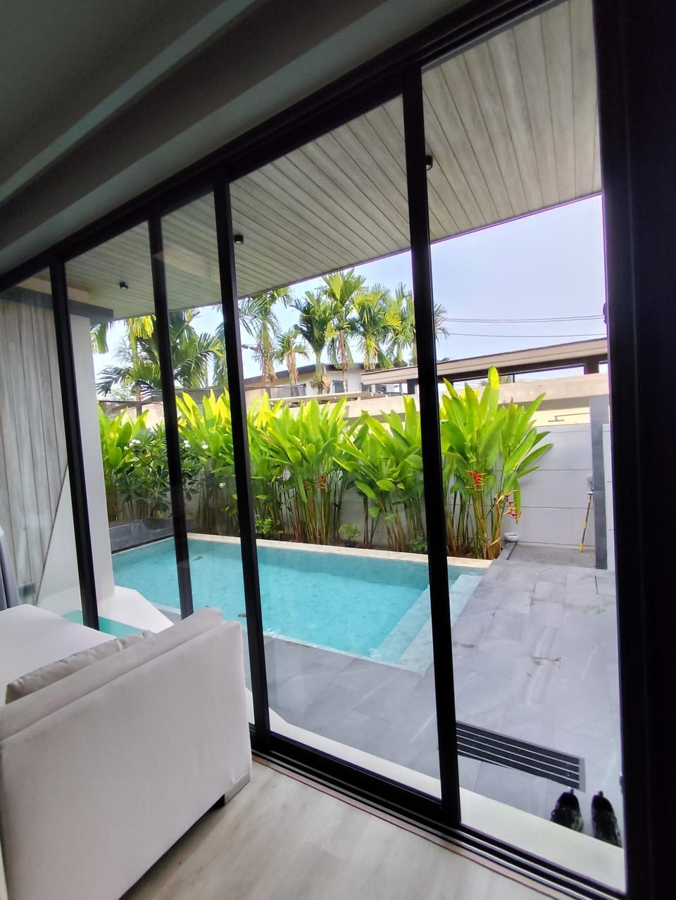The living room features a comfortable sofa and TV, perfectly positioned to enjoy relaxing views of the private pool.